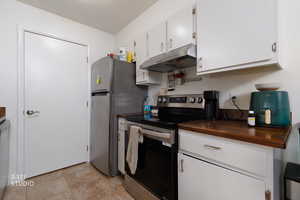 Kitchen featuring stainless steel appliances, white cabinets, and butcher block countertops