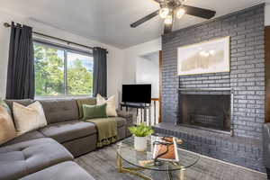 Living area with a ceiling fan, a brick fireplace, and a textured ceiling