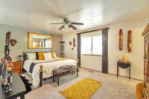Bedroom featuring a textured ceiling, carpet flooring, and ceiling fan