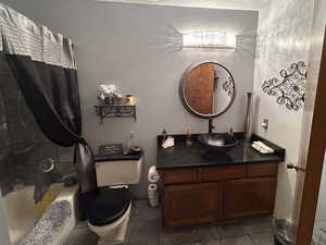 Bathroom featuring vanity, shower / bath combo, and dark tile patterned flooring