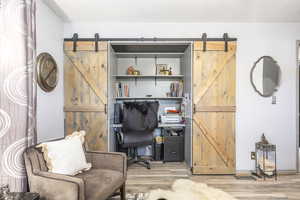 Office space with a barn door and light wood finished floors