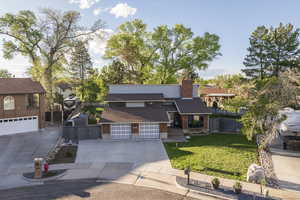 View of front facade with a gate, a chimney, brick siding, and driveway