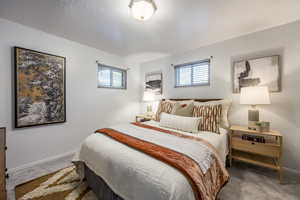 Carpeted bedroom featuring multiple windows and a textured ceiling