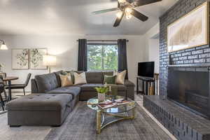 Living area with a brick fireplace, ceiling fan, and a textured ceiling
