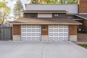 View of front facade with driveway, a shingled roof, and a garage