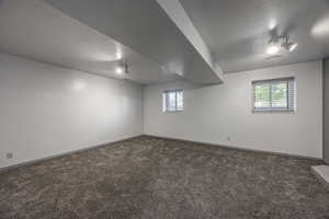 Below grade area featuring dark carpet and a textured ceiling