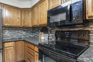 Kitchen with black appliances, wood finish cabinetry, and tasteful backsplash