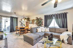 Carpeted living area featuring ceiling fan and a textured ceiling
