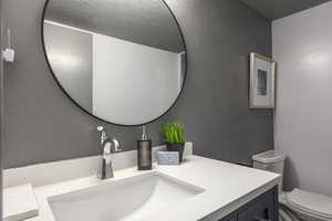Half bathroom featuring vanity and a textured wall