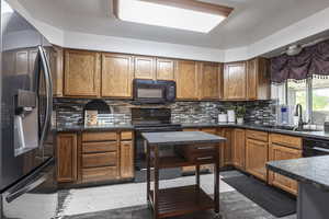 Kitchen with black appliances, wood finish cabinets, and tasteful backsplash