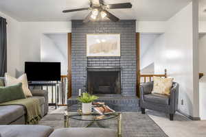 Carpeted living area featuring ceiling fan and a fireplace