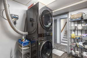 Laundry area featuring stacked washer / drying machine and dark wood-style floors