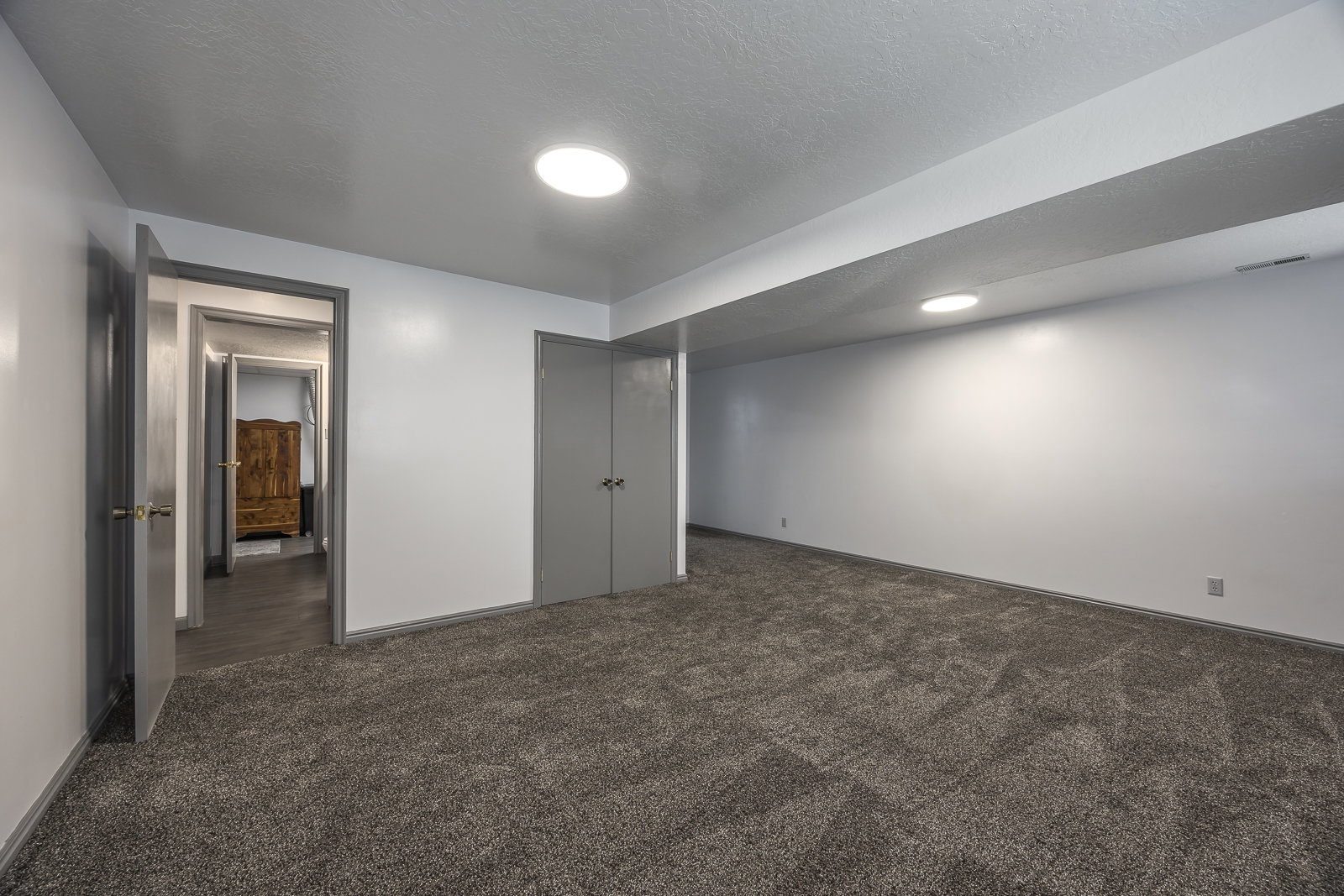 Finished basement with dark colored carpet and a textured ceiling