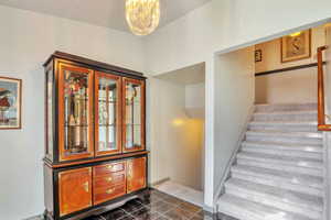 Stairs with tile patterned flooring and hanging lights