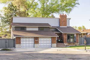 View of front of property featuring a gate, roof with shingles, a chimney, and concrete driveway