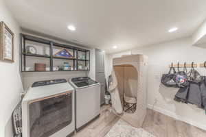 Laundry area featuring light wood-style floors, recessed lighting, and separate washer and dryer