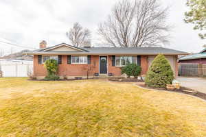 Ranch-style home with a chimney, brick siding, and a garage