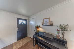 Entrance foyer featuring dark wood-style flooring and ornamental molding