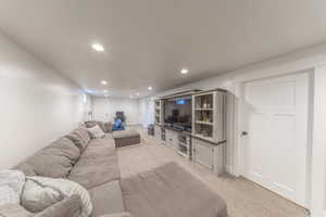 Living area with light colored carpet and recessed lighting