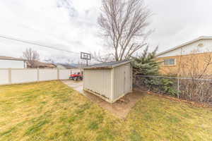 Fenced backyard featuring a storage unit