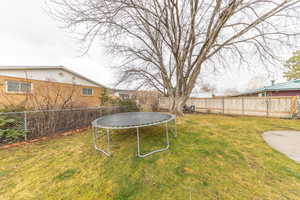 Fenced backyard featuring a trampoline