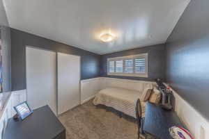 Bedroom with a decorative wall, wainscoting, carpet floors, and a closet