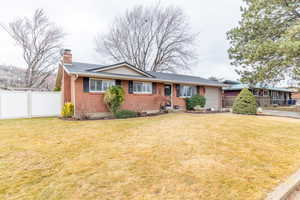 Ranch-style home featuring a chimney, brick siding, and a garage