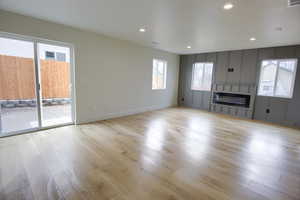 Unfurnished living room featuring a glass covered fireplace, light wood-style flooring, plenty of natural light, and recessed lighting