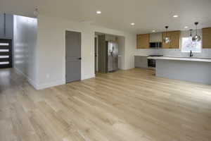 Kitchen featuring gray cabinetry, decorative light fixtures, decorative backsplash, light countertops, and stainless steel appliances