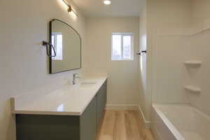 Bathroom with vanity, light wood-style flooring, shower / bathtub combination, and recessed lighting