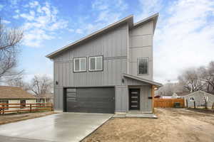 View of front of home with an attached garage, concrete driveway, and board and batten siding