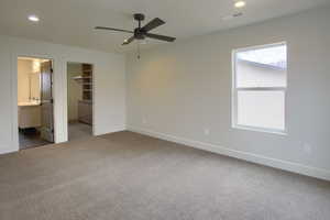 Unfurnished bedroom with a spacious closet, light carpet, recessed lighting, ceiling fan, and ensuite bathroom