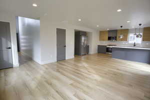 Kitchen featuring decorative backsplash, light countertops, stainless steel appliances, open floor plan, and hanging light fixtures