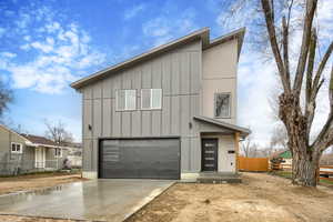 Contemporary house with an attached garage, concrete driveway, and board and batten siding