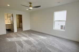 Unfurnished bedroom featuring a spacious closet, light carpet, connected bathroom, recessed lighting, and ceiling fan