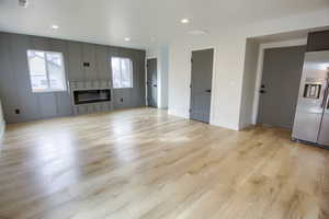 Unfurnished living room with light wood-style flooring, recessed lighting, and a large fireplace