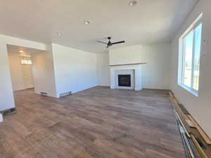 Unfurnished living room with dark wood-type flooring, ceiling fan, a tile fireplace, and recessed lighting