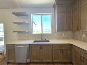 Kitchen featuring tasteful backsplash, open shelves, stainless steel dishwasher, light stone countertops, and dark wood-type flooring