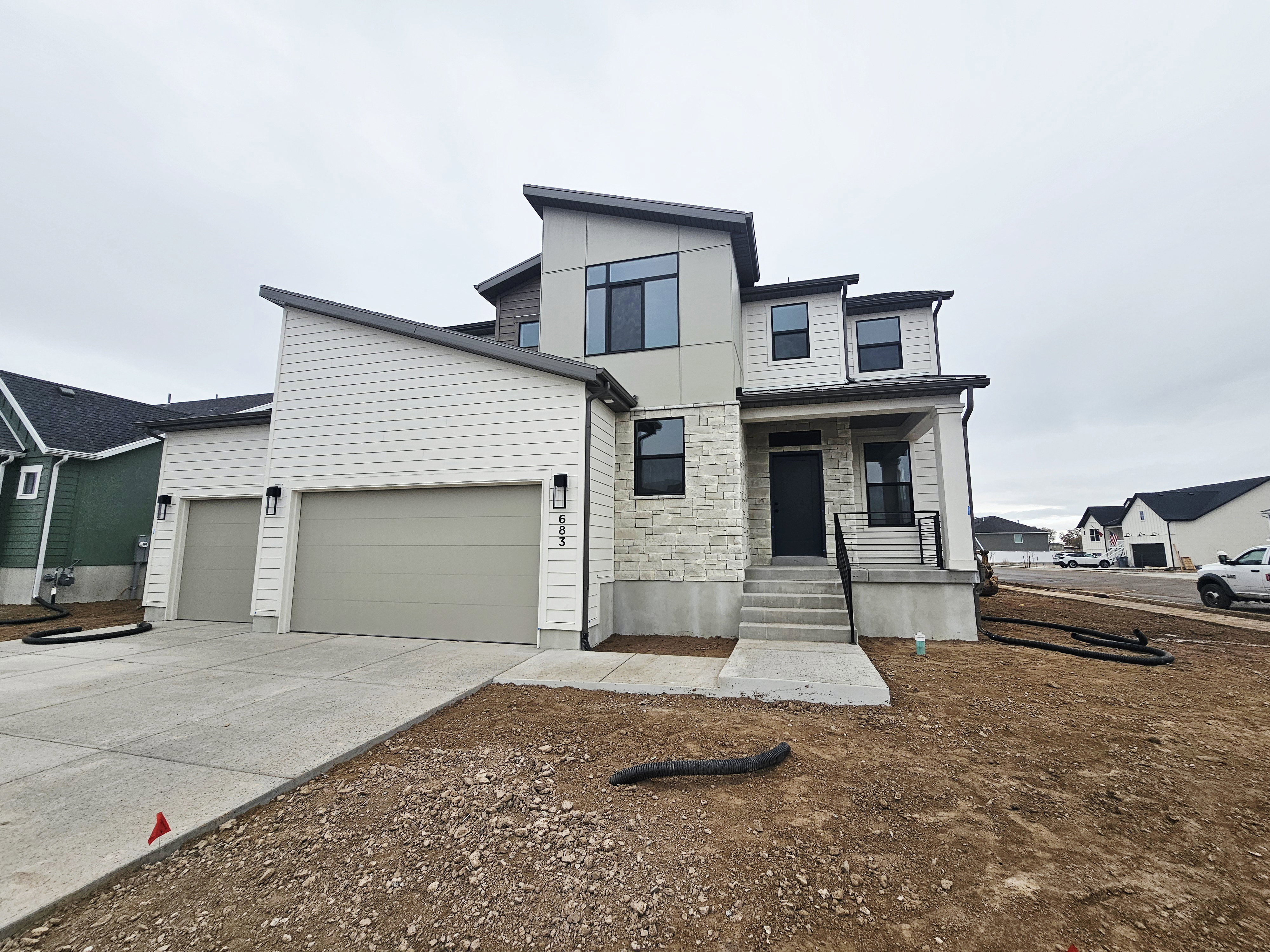 Contemporary house with stone siding, driveway, an attached garage, and a porch