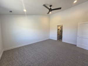 Unfurnished bedroom with dark carpet, a ceiling fan, connected bathroom, recessed lighting, and a high ceiling