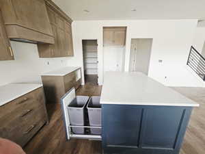Kitchen with light stone countertops, a center island, wood finish cabinets, dark wood finished floors, and recessed lighting
