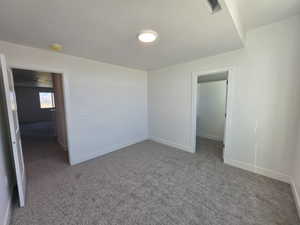 Unfurnished bedroom featuring a spacious closet and dark carpet