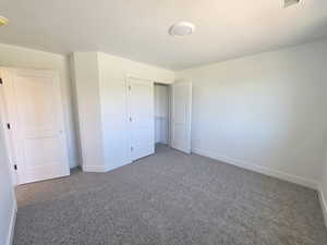 Unfurnished bedroom with dark colored carpet and a closet