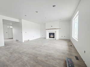 Unfurnished living room featuring light wood finished floors and a glass covered fireplace