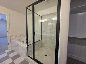 Bathroom featuring a marble finish shower and a bath