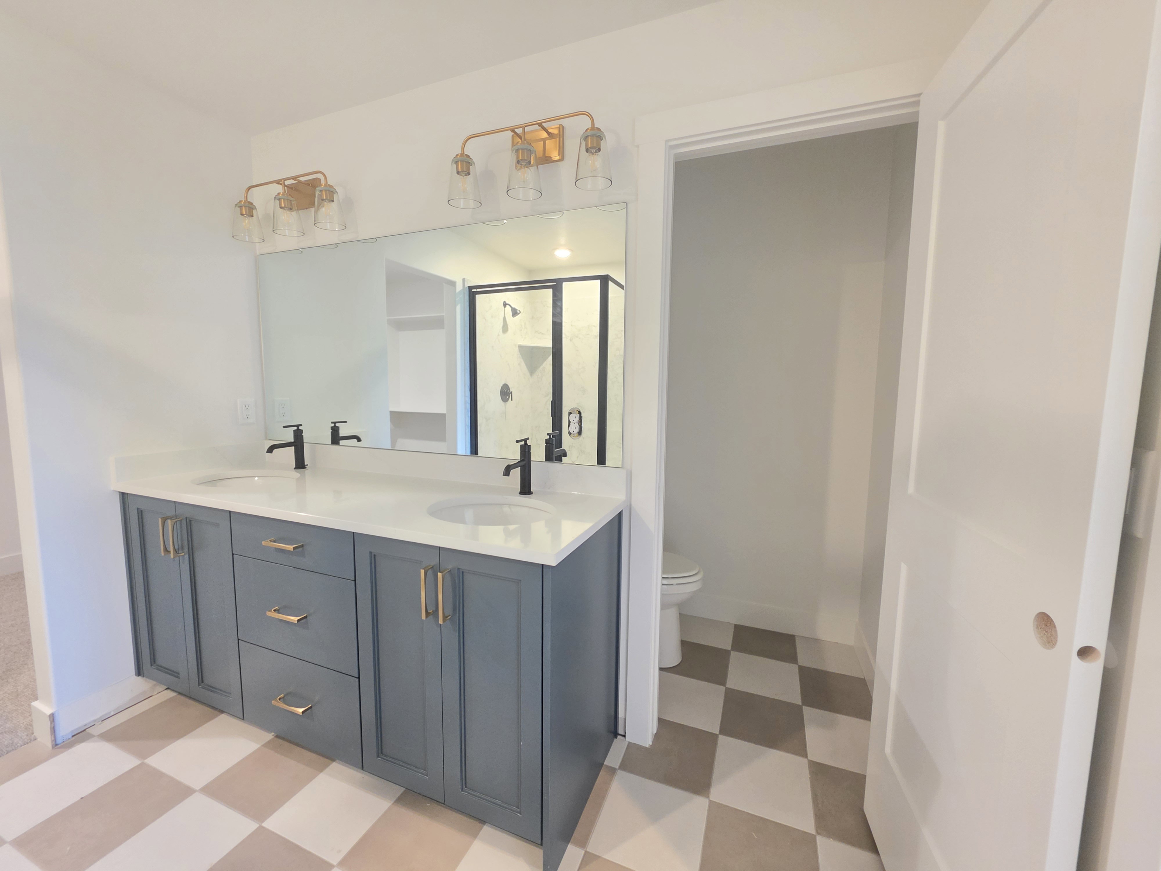 Bathroom with light flooring, double vanity, and a stall shower