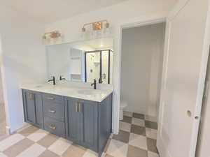 Bathroom with light flooring, double vanity, and a stall shower