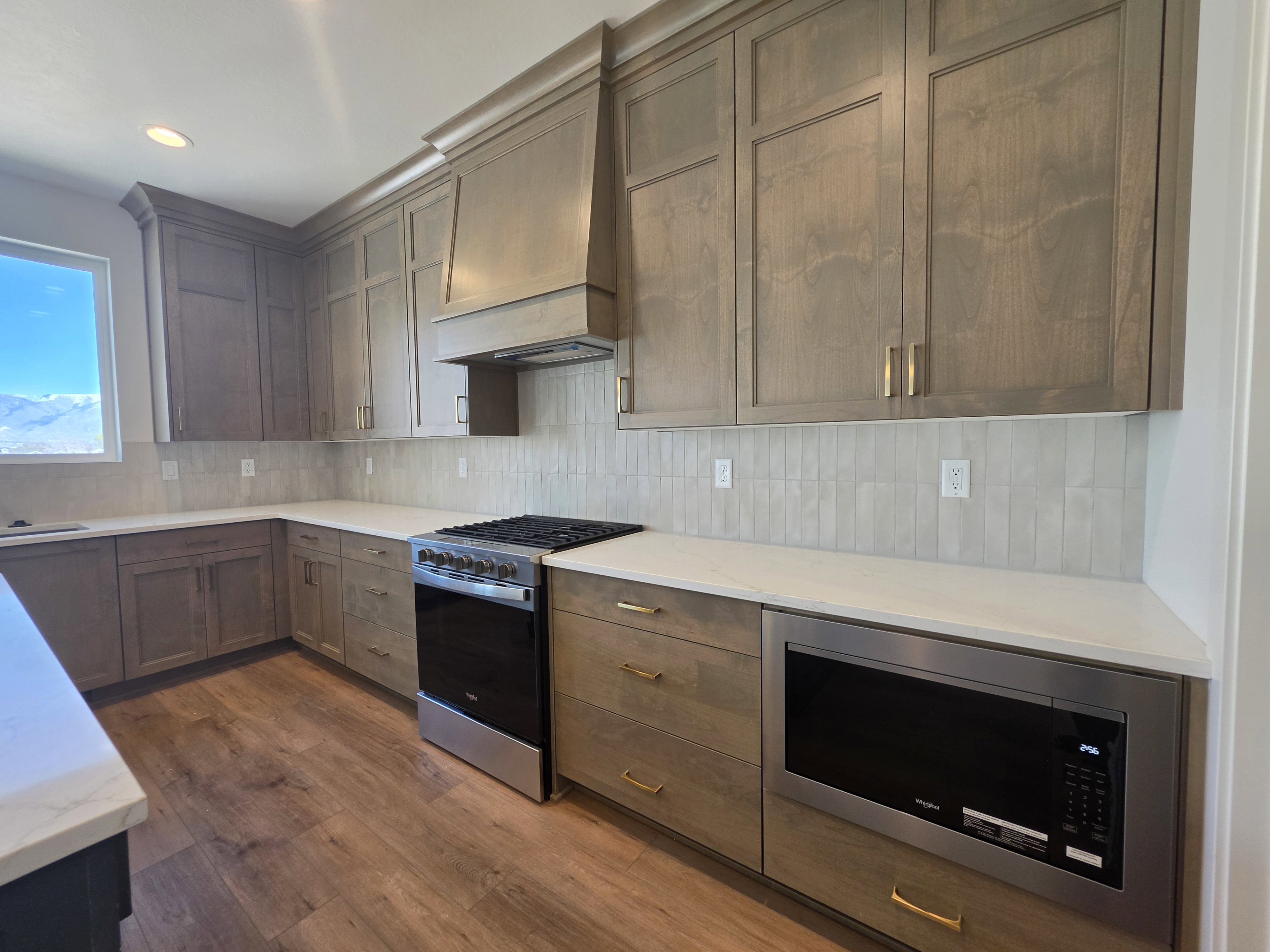 Kitchen with stainless steel appliances, backsplash, dark wood finished floors, light stone countertops, and recessed lighting