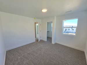 Unfurnished bedroom featuring a walk in closet and dark carpet