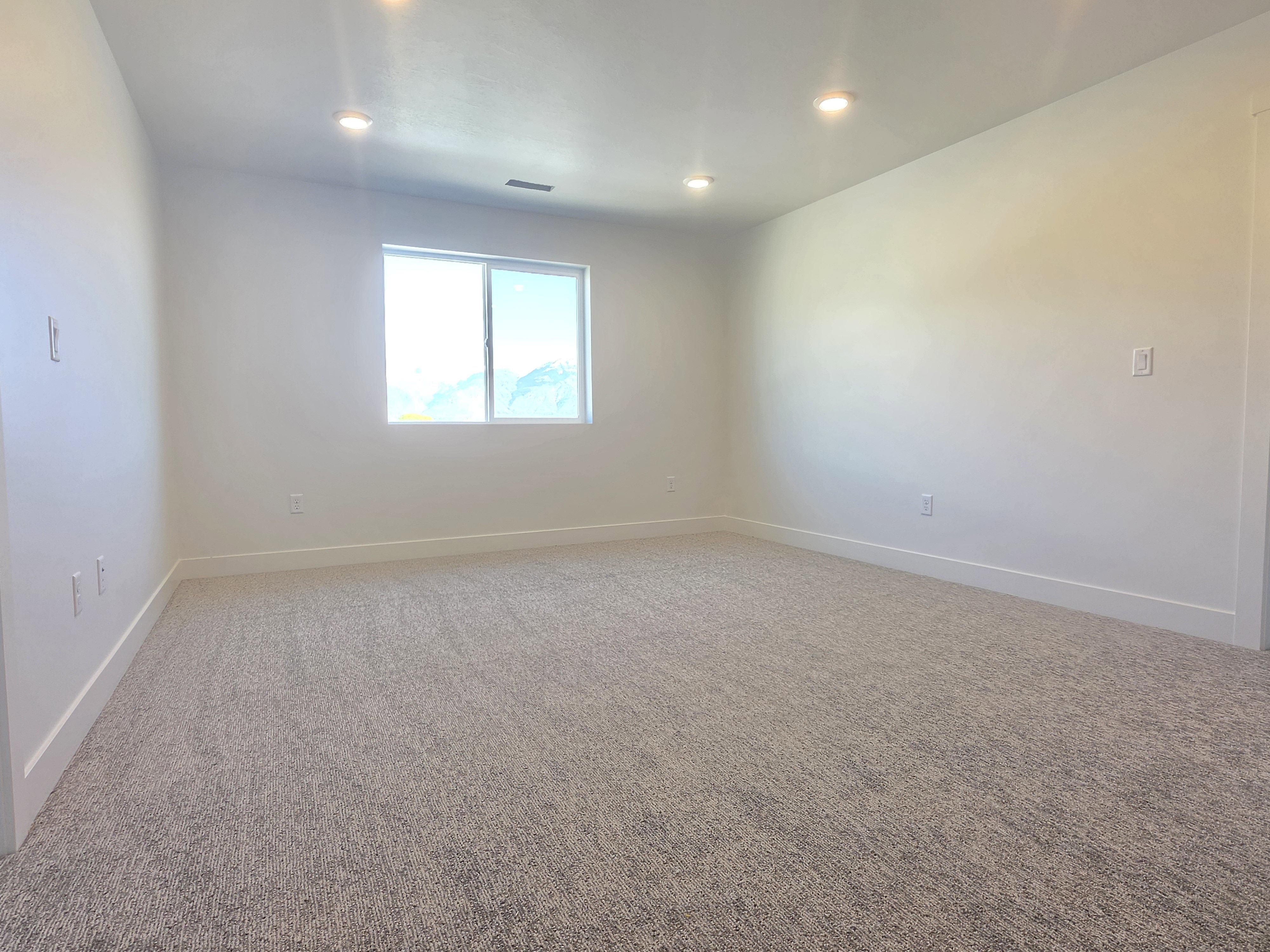 Carpeted spare room with baseboards and recessed lighting